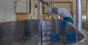 Homem fazendo o serviço de limpeza e sanitização na indústria de alimentos.