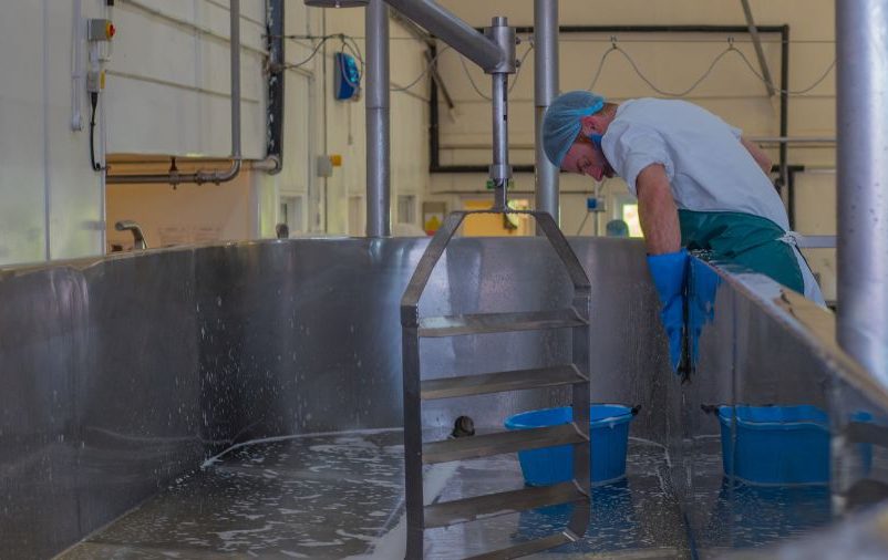 Homem fazendo o serviço de limpeza e sanitização na indústria de alimentos.