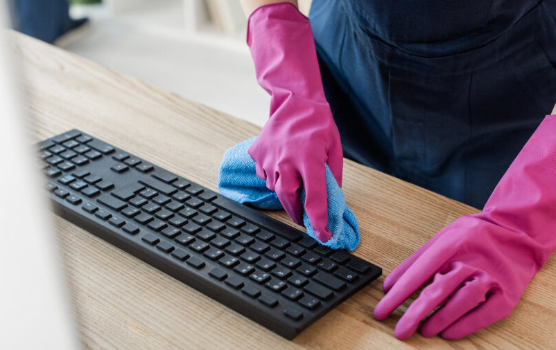 Mulher limpando teclado para deixar o ambiente limpo