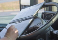 Veja os benefícios de ter um motorista terceirizado! Detalhe de mãos e papéis sobre o volante, pautando o serviço de motorista terceirizado.